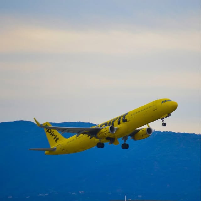 Spirit Airlines jet climbing past blue hills at San Jose airport